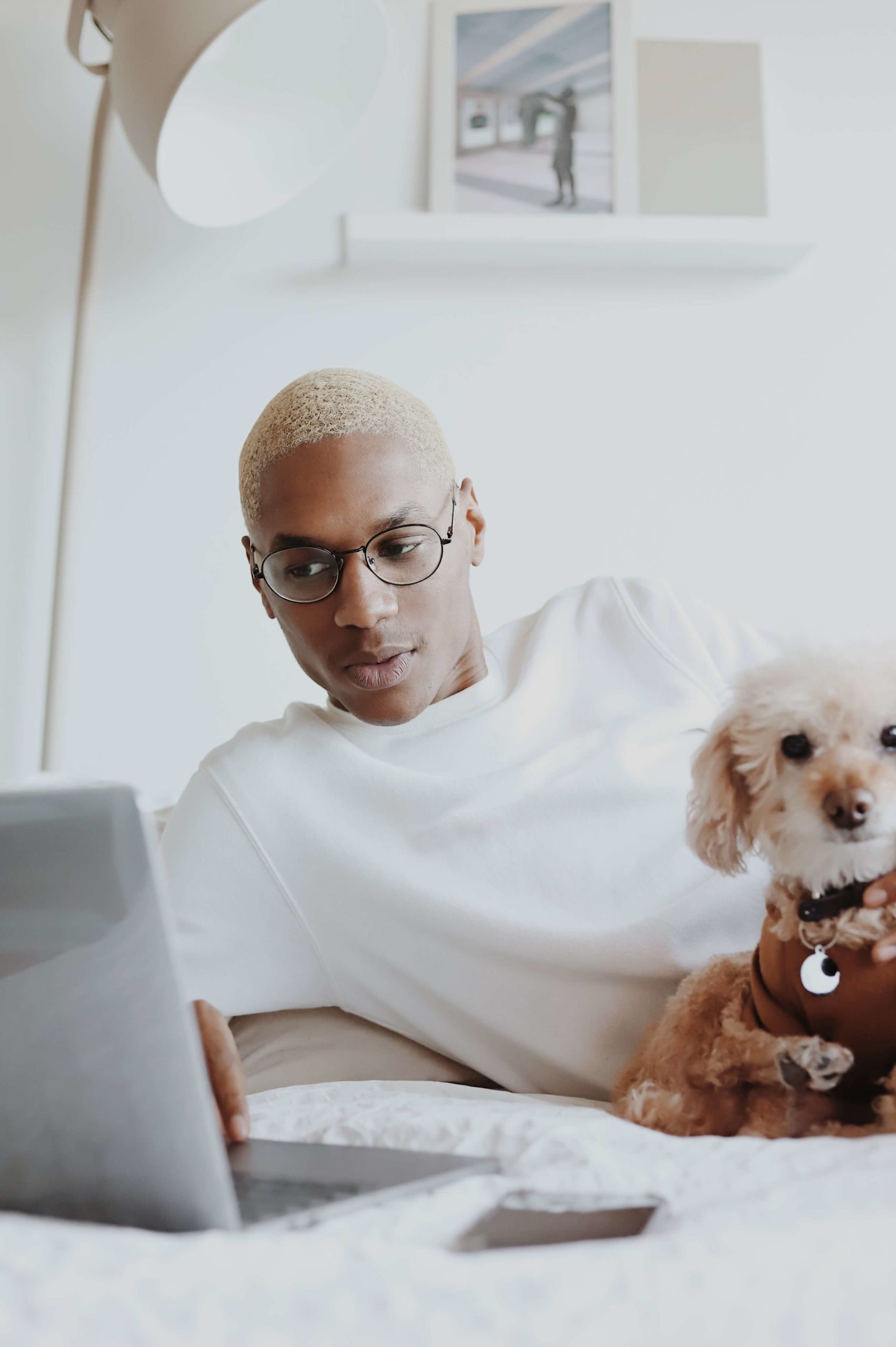 person with glasses looking at laptop with dog