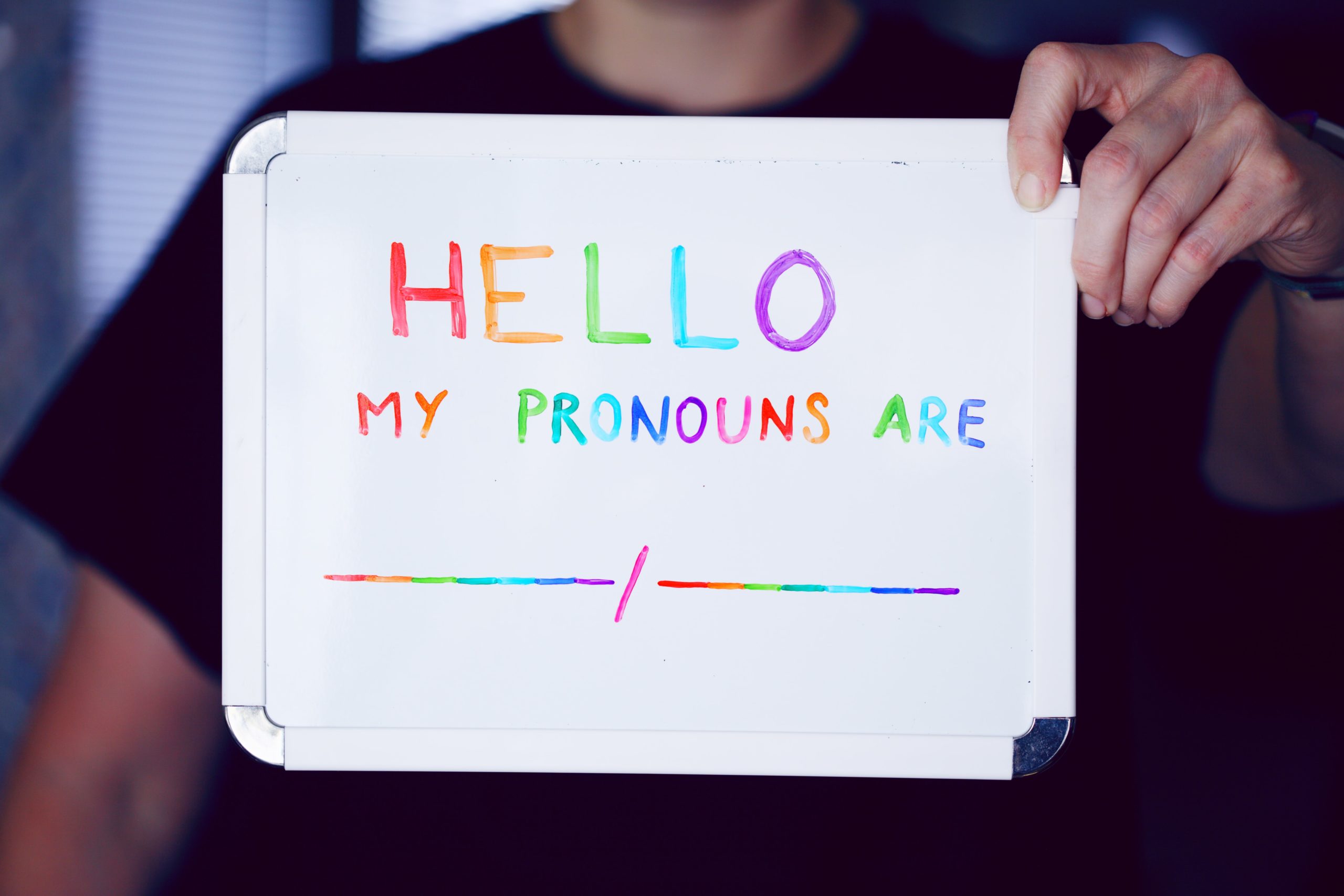 white board sign that says "Hello, my pronouns are"