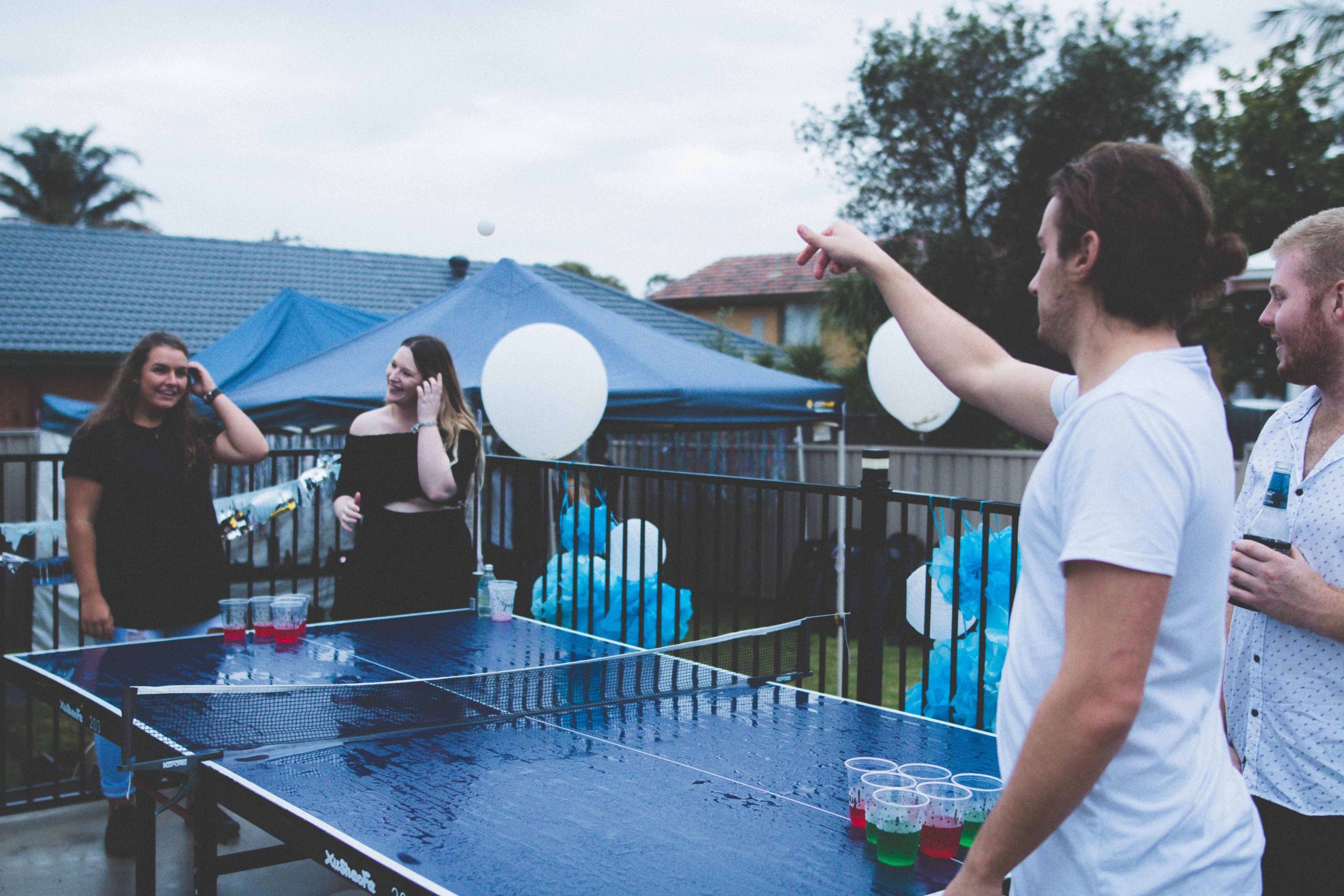 four students playing beer pong