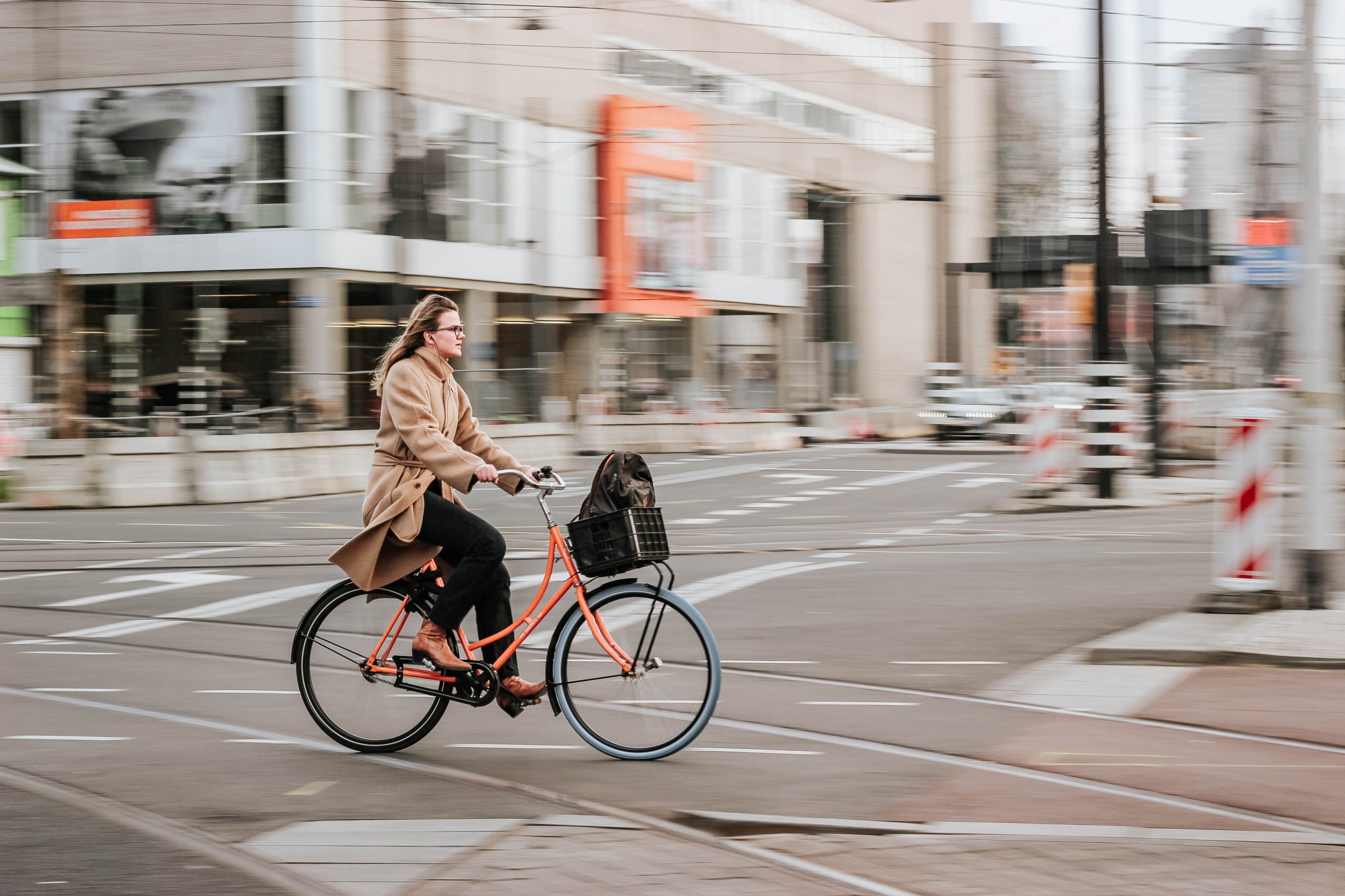 woman in brown coat on a bike
